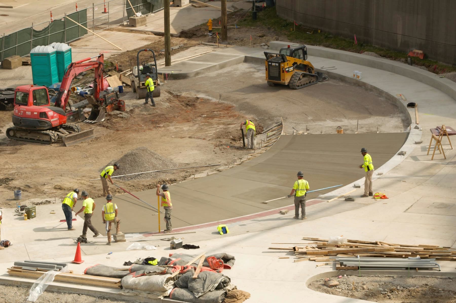 HD Grading crew placing and finishing a curved concrete slab on a commercial site