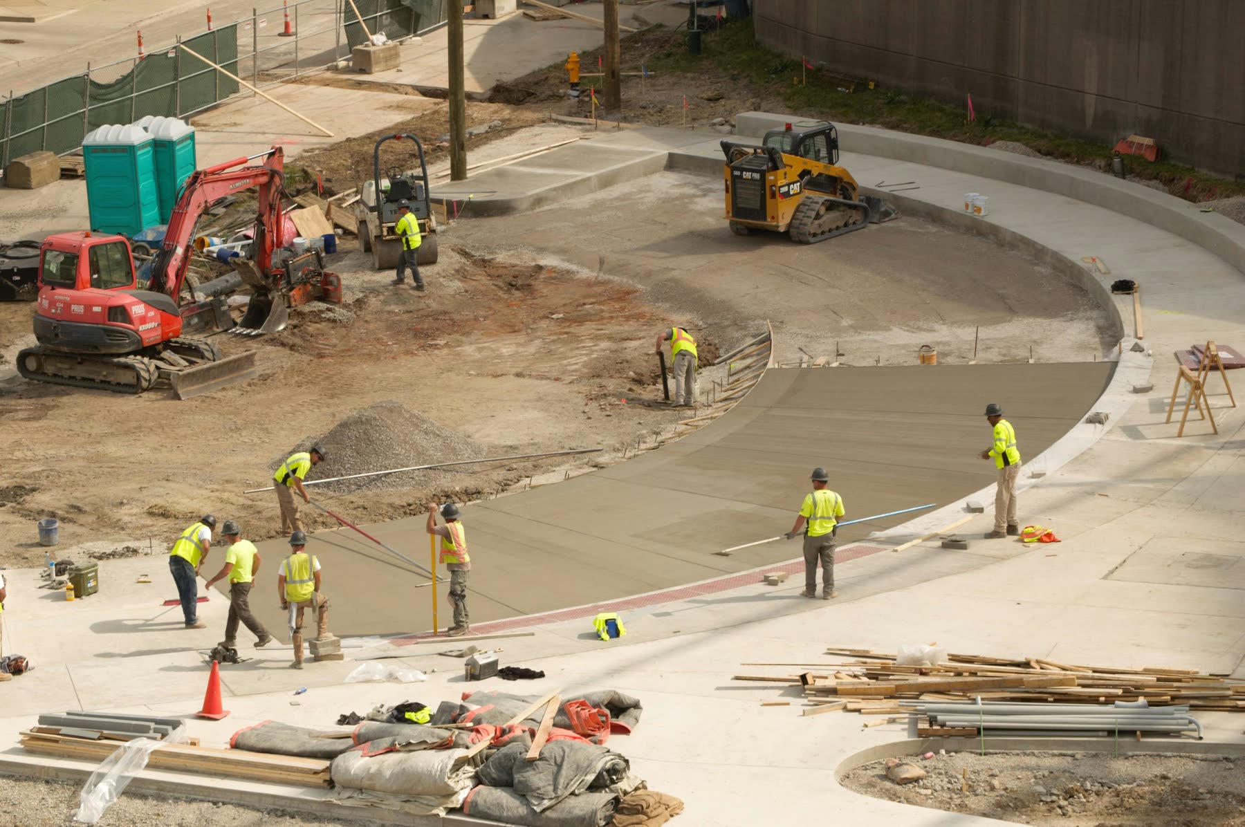 HD Grading crew placing and finishing a curved concrete slab on a commercial site